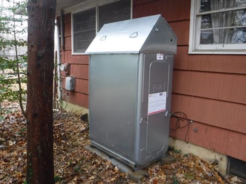 Outdoor Roth oil tank installation with weather hood next to a Long Island home