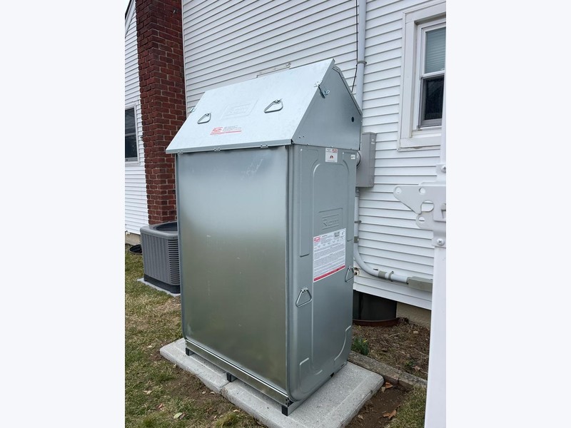 Roth double-wall oil tank installed outdoors on concrete pavers next to home exterior